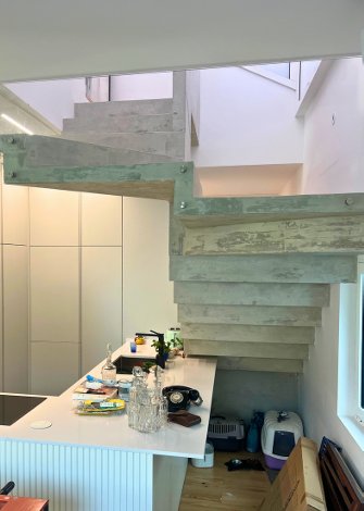 Escada flutuante de betão em espaço moderno com cozinha