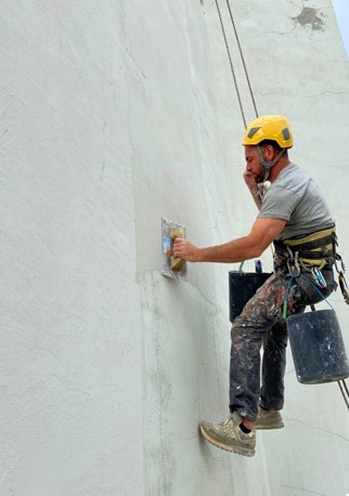 Trabalho em altura — técnico a aplicar reboco em fachada